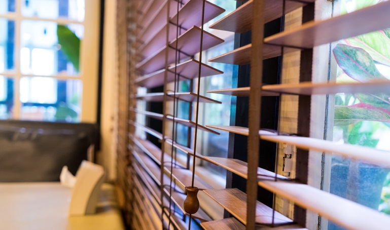 Kobieta wygląda przez okno z żaluzjami