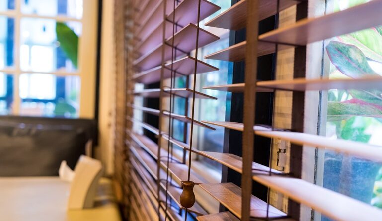 Kobieta wygląda przez okno z żaluzjami